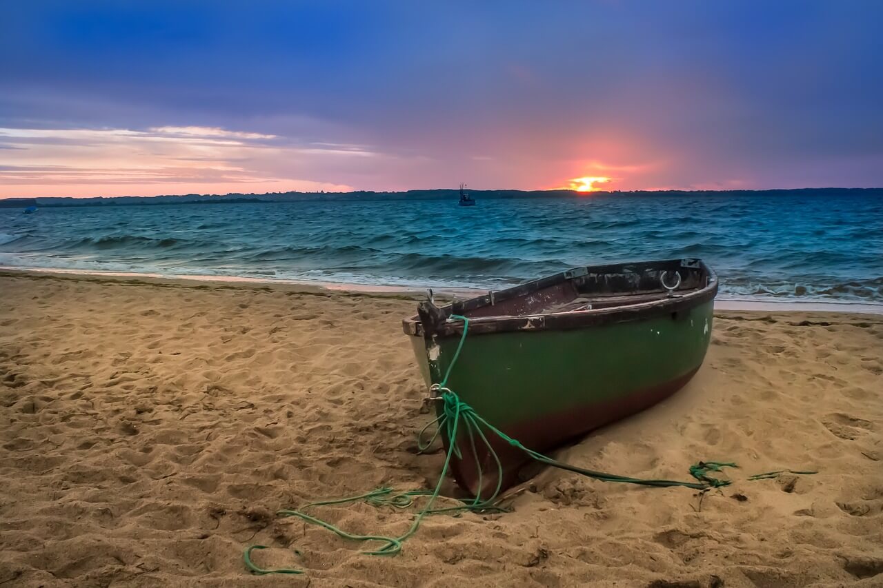 Widok zachodu słońca z łódką na brzegu.